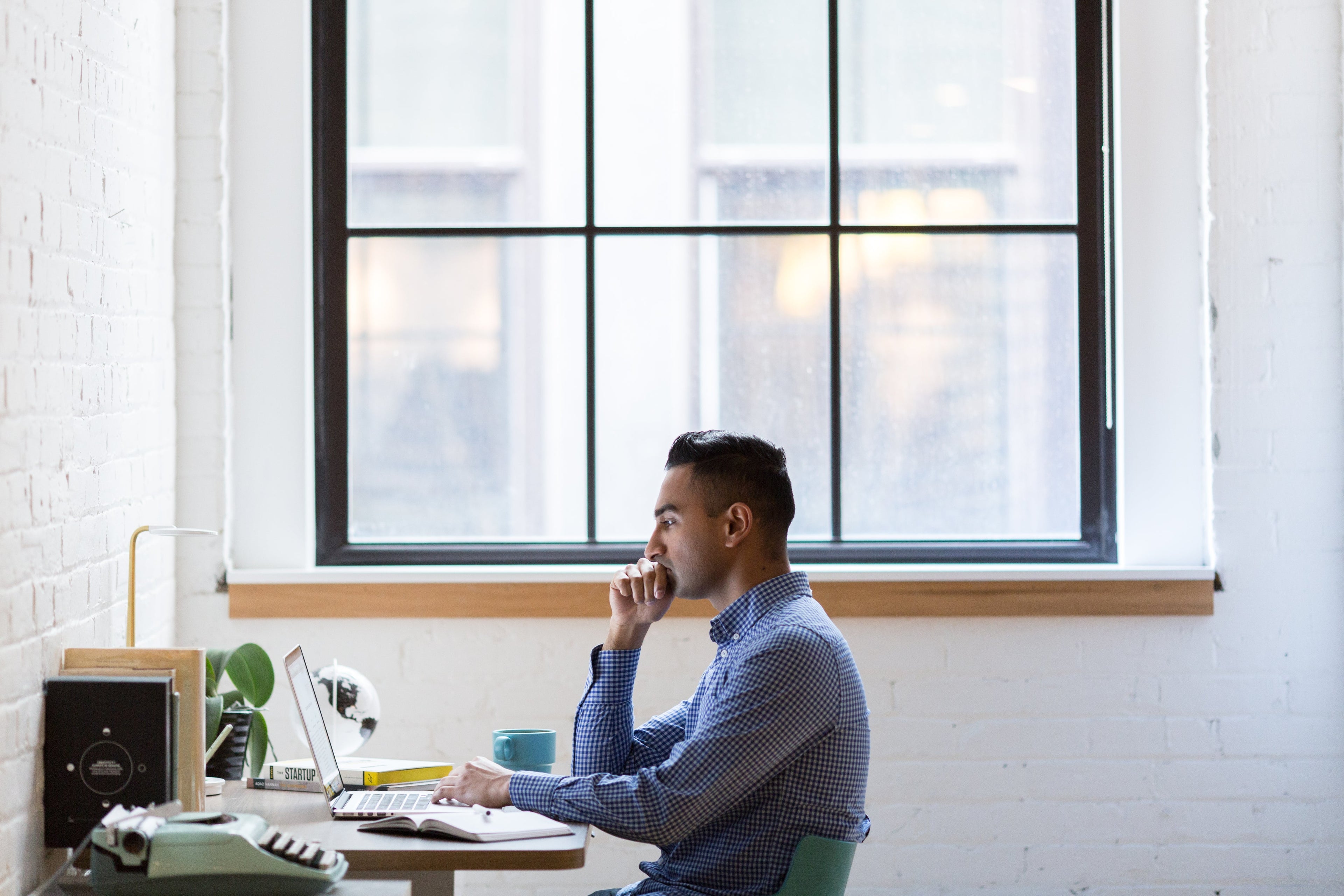 Man sitting at a desk in an office with large windows